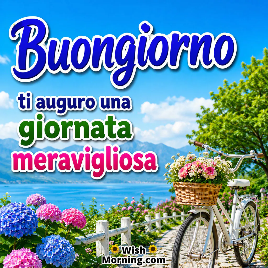 Buongiorno Morning Wish Image featuring a bright blue sky, fluffy white clouds, colourful flowers and a peaceful lakeside landscape symbolising a fresh and cheerful start to the day.